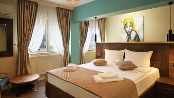 A hotel room with a large bed, a wooden headboard, a round table, and a painting on the wall.