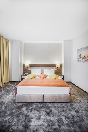 Camera d'albergo con un letto grande, un comodino, una lampada, un telefono e un quadro appeso al muro.