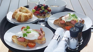 A tray with breakfast items including croissant, toast with ham and egg, and a fruit bowl. - Hotel Marshal (Belgrade)