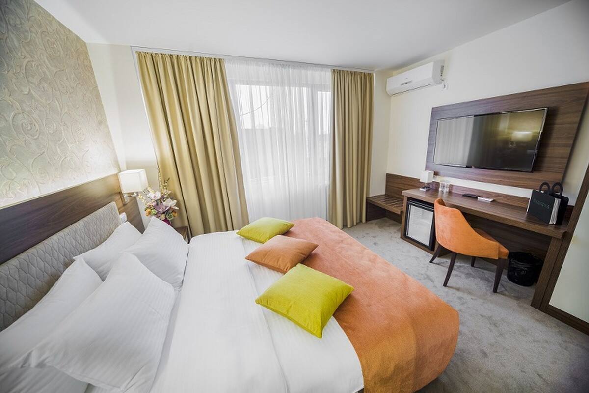 A hotel room with a bed, a desk, a television, and a chair.