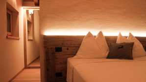 Une chambre à coucher avec une tête de lit en bois, un lit avec une literie blanche et un oreiller orné d’un logo.