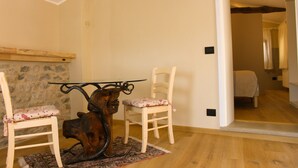 Un coin repas avec une table en bois rustique et deux chaises, un mur en pierre et un plancher en bois.