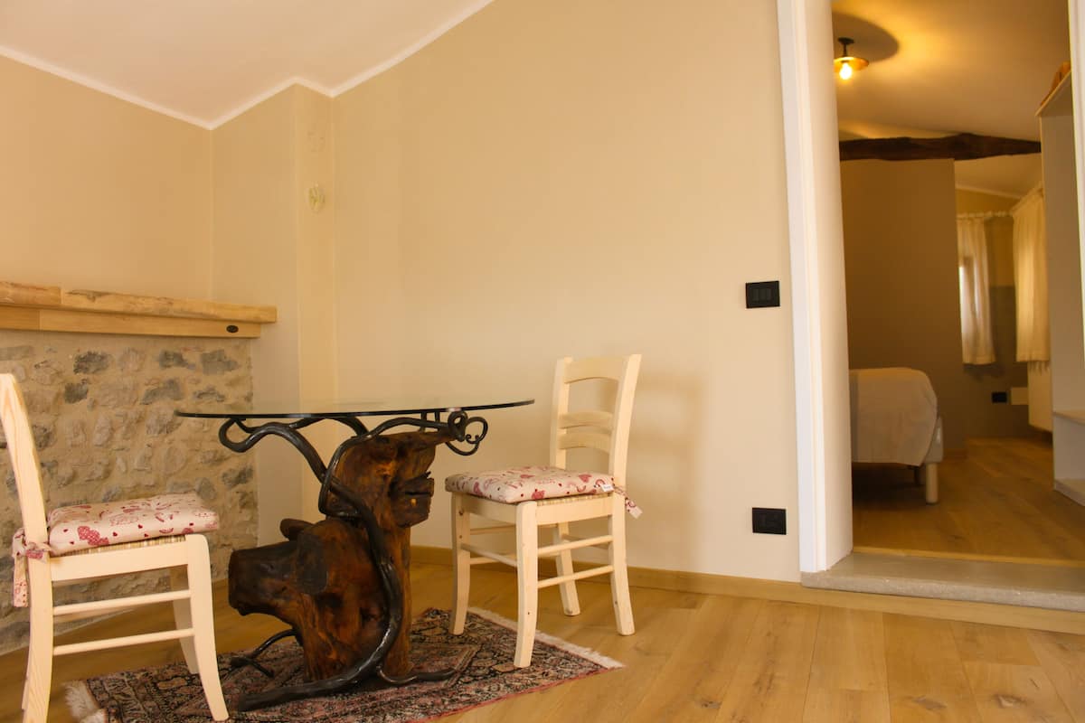 Un coin repas avec une table en bois rustique et deux chaises, un mur en pierre et un plancher en bois.