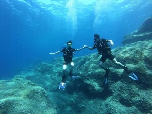 Dos buzos bajo el agua con aletas y equipo de buceo.