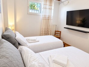 A hotel room with two beds, a TV mounted on the wall, and a window with curtains. - Eagles Nest Villa Your Grecian Paradise (Kropia)