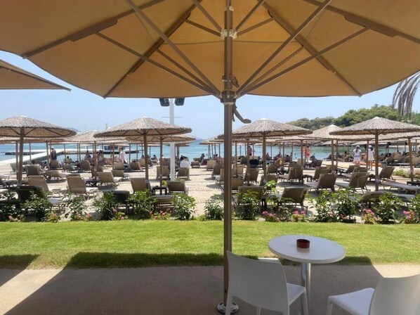 Un espace de détente aménagé sur la plage, avec des parasols, des chaises longues et une piscine.