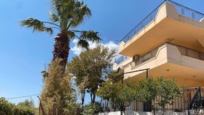 Un edificio de varios pisos con balcones, una palmera y una pared blanca.