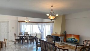 Un salón amplio con comedor, chimenea y televisor.