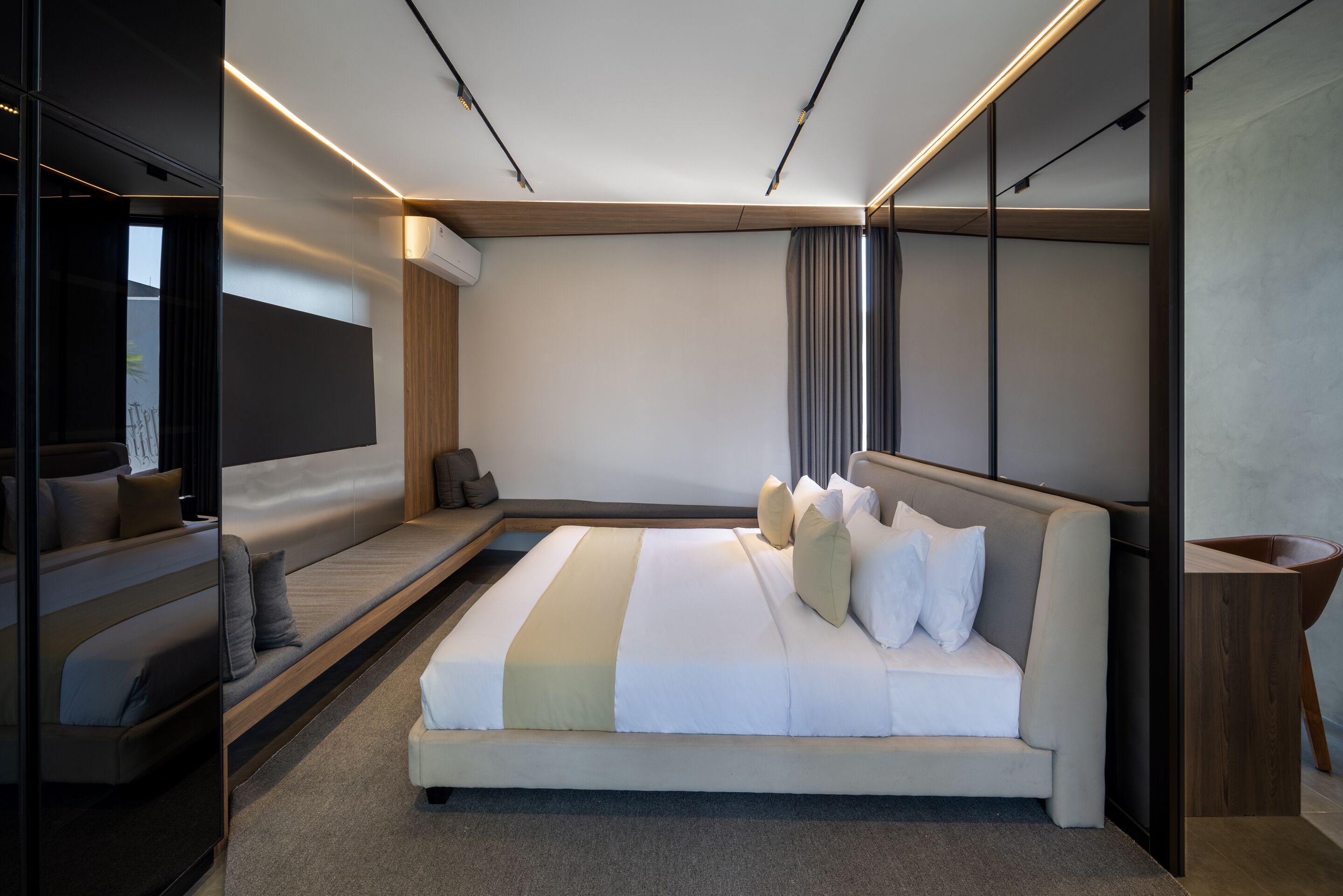 A modern hotel room with a large bed, a sofa, and a small table.