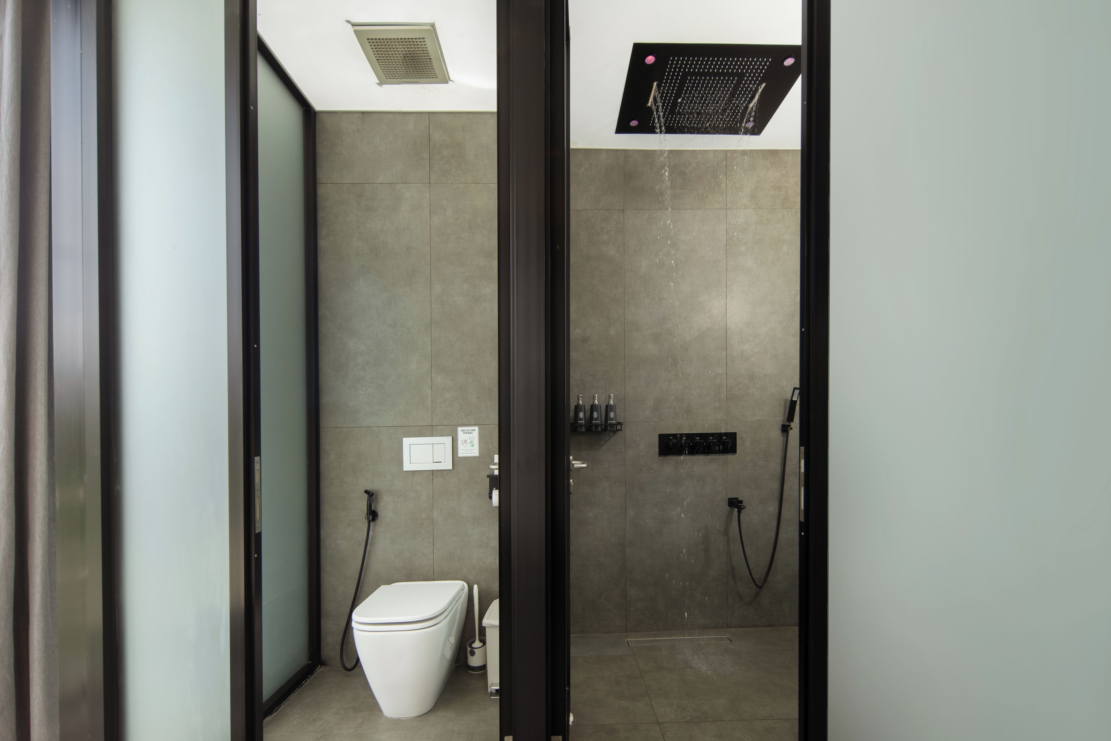 A modern bathroom with a toilet, shower, and sink.