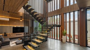 A modern interior with a spiral staircase, a flat-screen TV, and a seating area. - Alex Villas Complex N2 (Canggu)