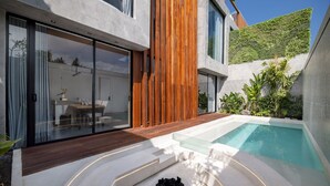 A modern house with a glass-enclosed patio, a swimming pool, and a wooden deck. - Alex Villas Complex N2 (Canggu)