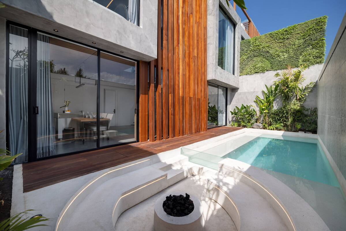 A modern house with a glass-enclosed patio, a swimming pool, and a wooden deck.
