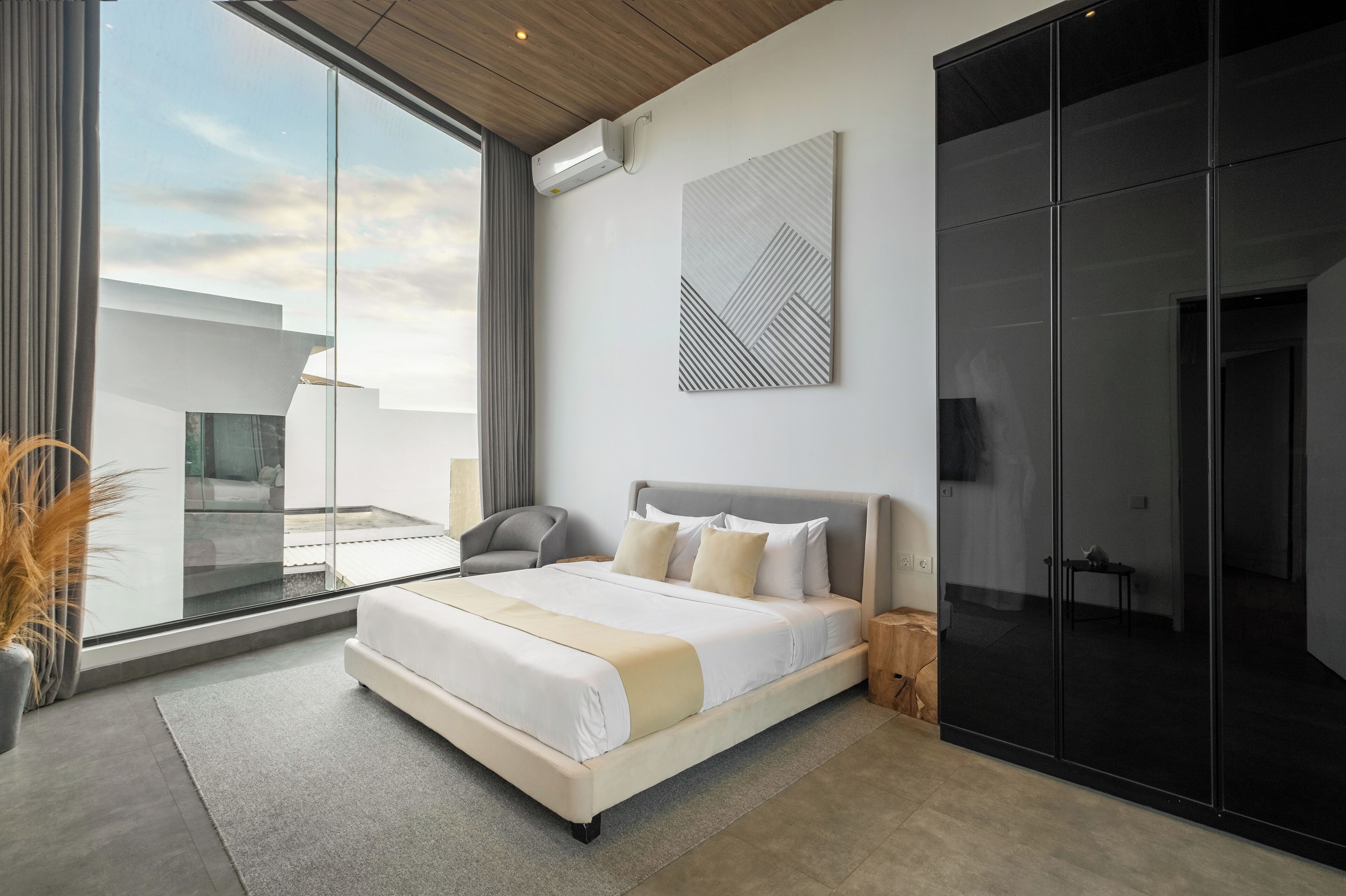 Un dormitorio moderno con una cama grande, vista al cielo y puerta corredera hacia un balcón.