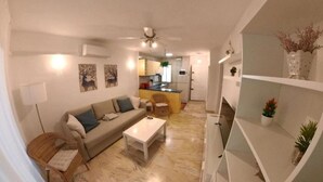A living room with a sofa, coffee table, and a dining area with a chair. - Poseidón. Beachfront apartment (Fuengirola)