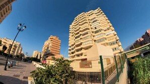 A high-rise building with multiple balconies, a gated entrance, and a clear sky. - Poseidón. Beachfront apartment (Fuengirola)