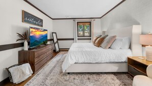 Une chambre à coucher avec un lit, une télévision, une commode, une fenêtre et une citation inspirante sur le mur.