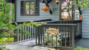 Une maison en bois avec un porche, une enseigne indiquant « Beech Retreat », et une boîte aux lettres.