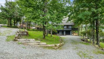 A residential property with a gravel driveway, wooden steps, and a two-story house with a balcony.