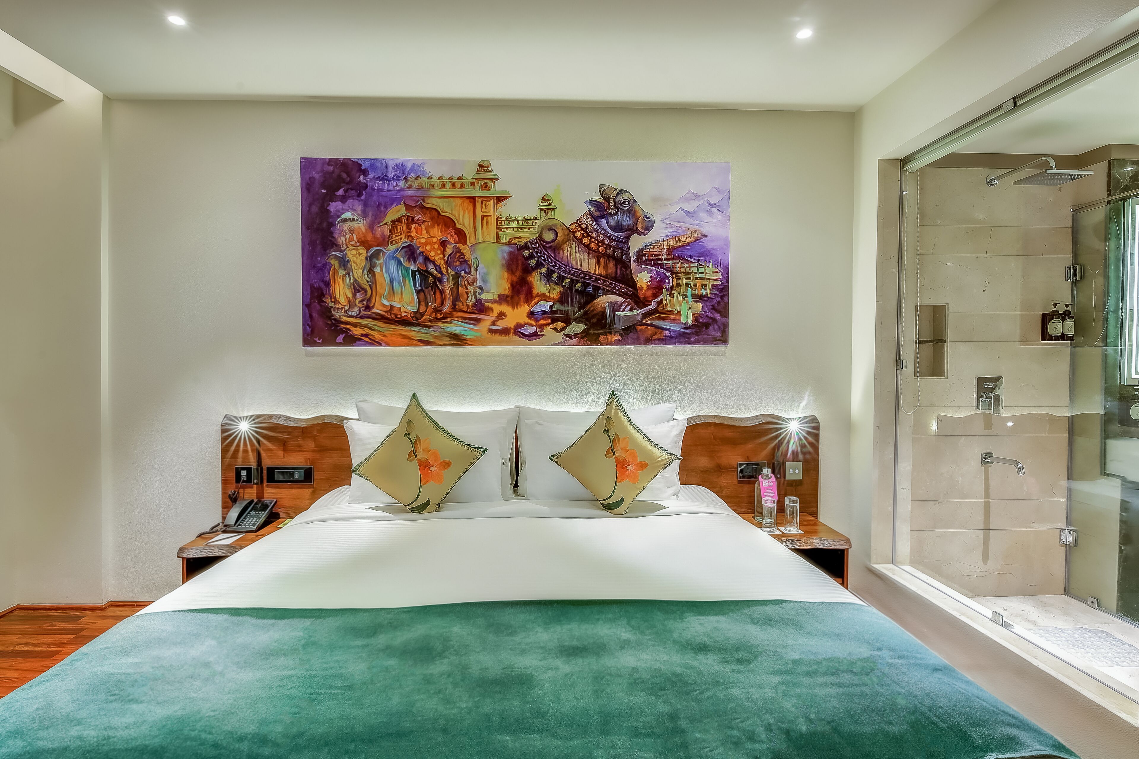 A hotel room with a large bed, a glass shower enclosure, and a colorful mural on the wall.