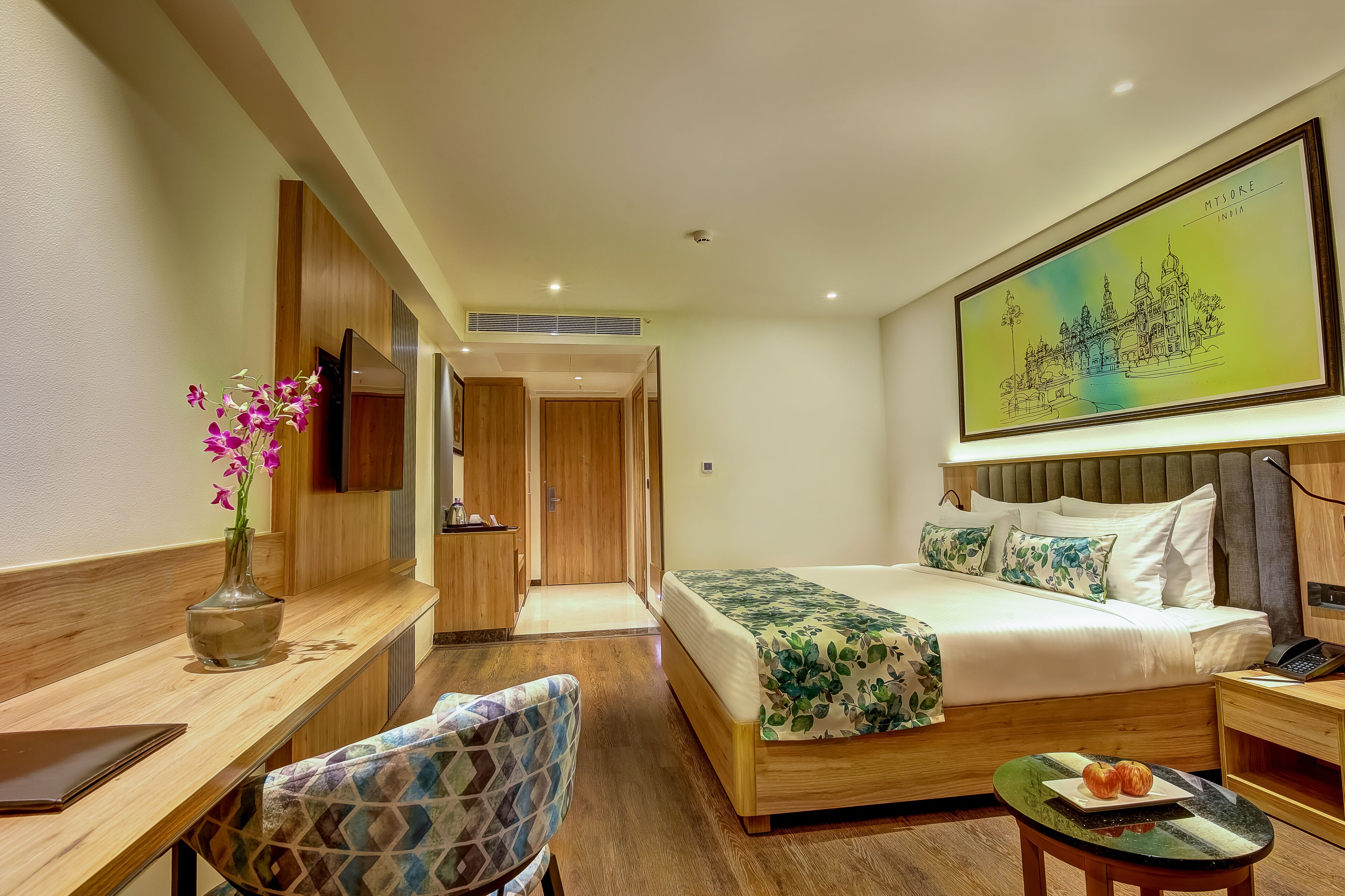 Une chambre d’hôtel avec un lit, un bureau, une chaise, une petite table et un tableau au mur.