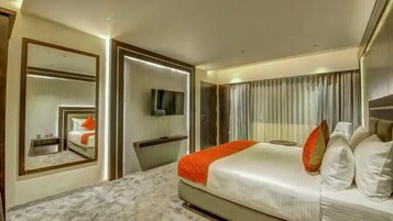 Una habitación de hotel moderna con una cama grande, televisión, espejo y armario.