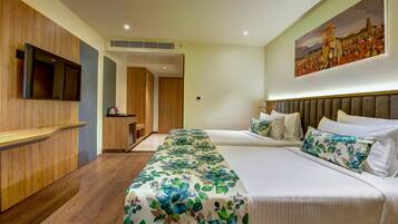 A hotel room with a large bed, a TV mounted on the wall, and a painting above the bed.