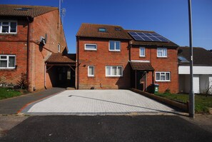A residential building with a paved driveway, solar panels on the roof, and a garage.