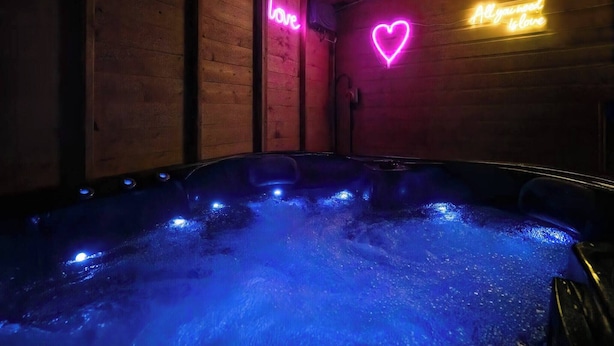A hot tub with neon signs on the walls, surrounded by wooden paneling. - Get Away Home With Hot Tub Sleeps 7 (Peacehaven)
