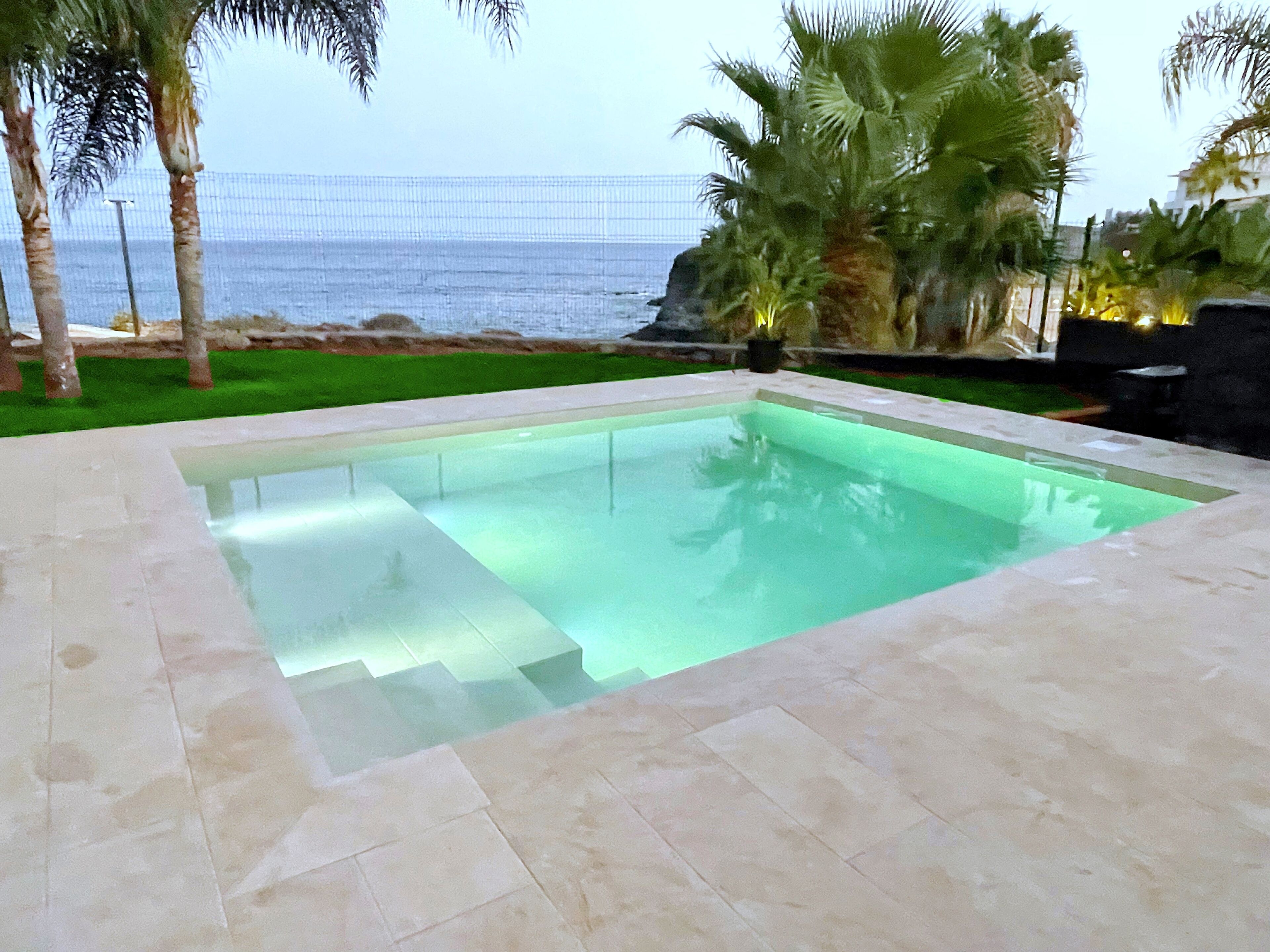 Una piscina rettangolare con acqua cristallina, circondata da un solarium piastrellato.