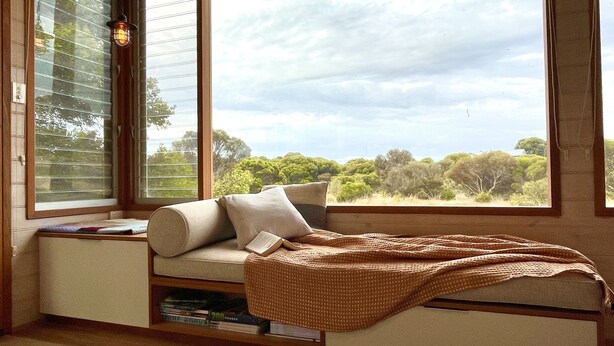 Une pièce confortable avec un lit intégré, une fenêtre avec des stores et une vue sur les arbres et le ciel.