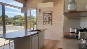 Une cuisine moderne avec un îlot central en bois, un lave-vaisselle encastré et une grande fenêtre offrant une vue panoramique.