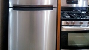 A stainless steel refrigerator and a gas stove in a kitchen with wooden cabinets and a tiled backsplash. - A peice of paradise,large luxury condominium beautiful space cozy & homely!!!!!! (Nassau)