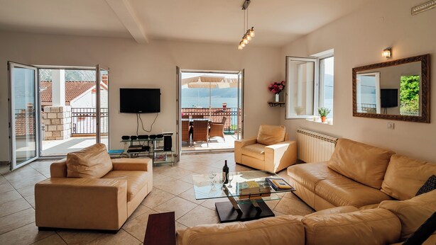 Ein Wohnzimmer mit einer Couch, einem Couchtisch, einem Fernseher und einem Balkon mit Blick.