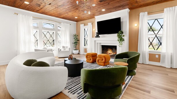 A modern living room with a fireplace, wooden ceiling, and large windows.