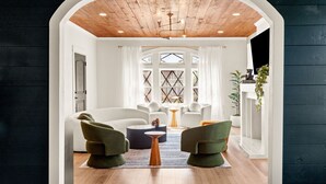 A modern living room with a white sofa, green armchairs, and a coffee table.