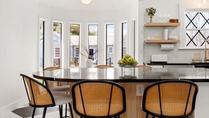 A modern kitchen with a large island, white cabinetry, and a view of the outside.
