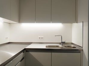 Een moderne keuken met een rvs aanrecht, een dubbele spoelbak en ingebouwde kasten.