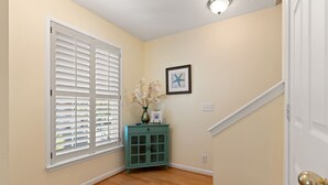 Un couloir avec un plancher en bois, une armoire de couleur turquoise, une œuvre d’art encadrée et une porte blanche.