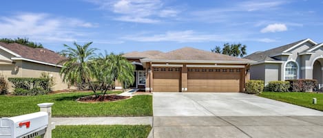 A residential house with a garage, a driveway, and a mailbox.