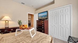 A hotel room with a bed, a dresser, a television, and a door. - Valrico's Hidden Gem: A Stunning 3-Bedroom Oasis Awaits! (Valrico)