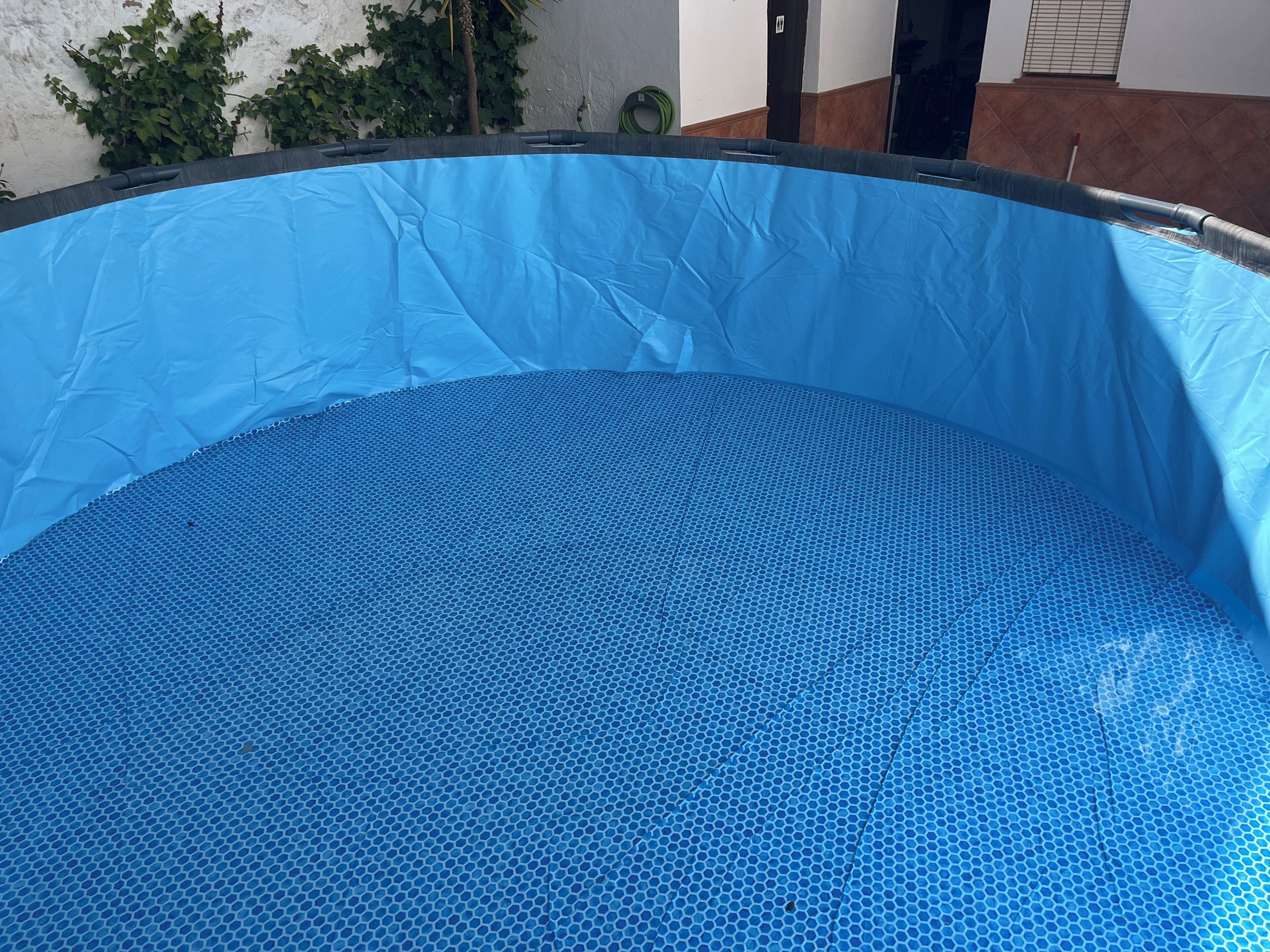 An indoor swimming pool with a blue textured floor and a blue cover.