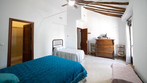 A bedroom with two beds, a wooden dresser, and a ceiling fan. - El Parador de Carmencita Casa Rural Capacidad 19 Personas (Almedinilla)