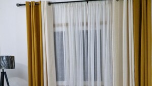 Moderni olohuone, jossa on kulmasohva, rottinkinen sivupöytä ja lattiavalaisin.