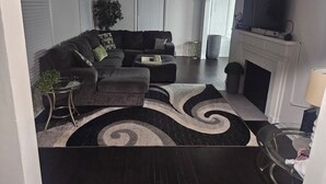 Olohuoneessa on kulmasohva, sohvapöytä, takka ja televisio.