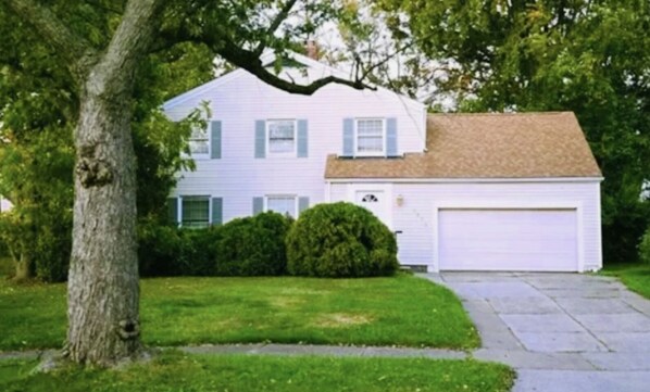 A single-story house with a garage, surrounded by a well-maintained lawn and a large tree.