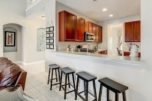 Una cocina moderna con armarios de madera, un microondas y una zona de bar con taburetes.