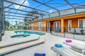 Un espacio al aire libre cubierto con piscina, sillas de descanso y un patio con mesas y sillas.