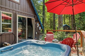 A hot tub on a deck with a red umbrella, surrounded by trees and a wooden deck. - Retro A-Frame • Hot Tub • Firepit • Stevens Pass (Skykomish)