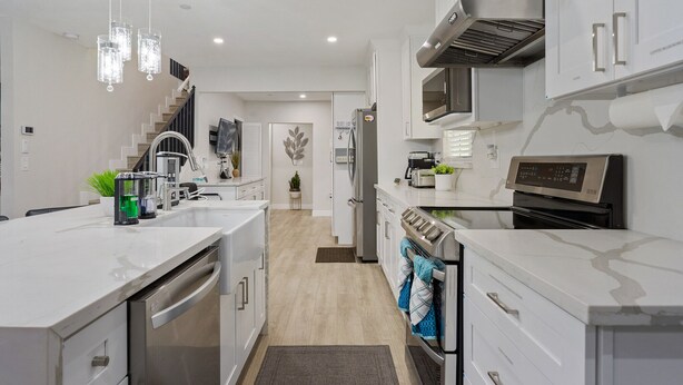 A modern kitchen with white cabinetry, stainless steel appliances, and a central island.